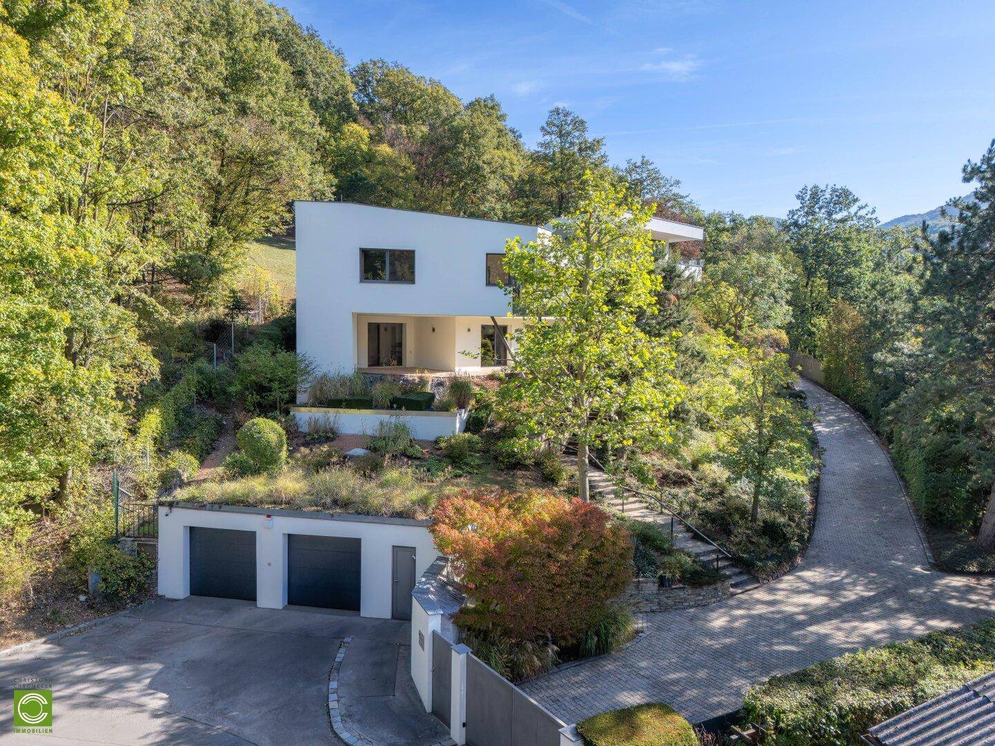 Modernes Wohnhaus mit integrierter Doppelgarage und begrünter Dachfläche in Hanglage.
