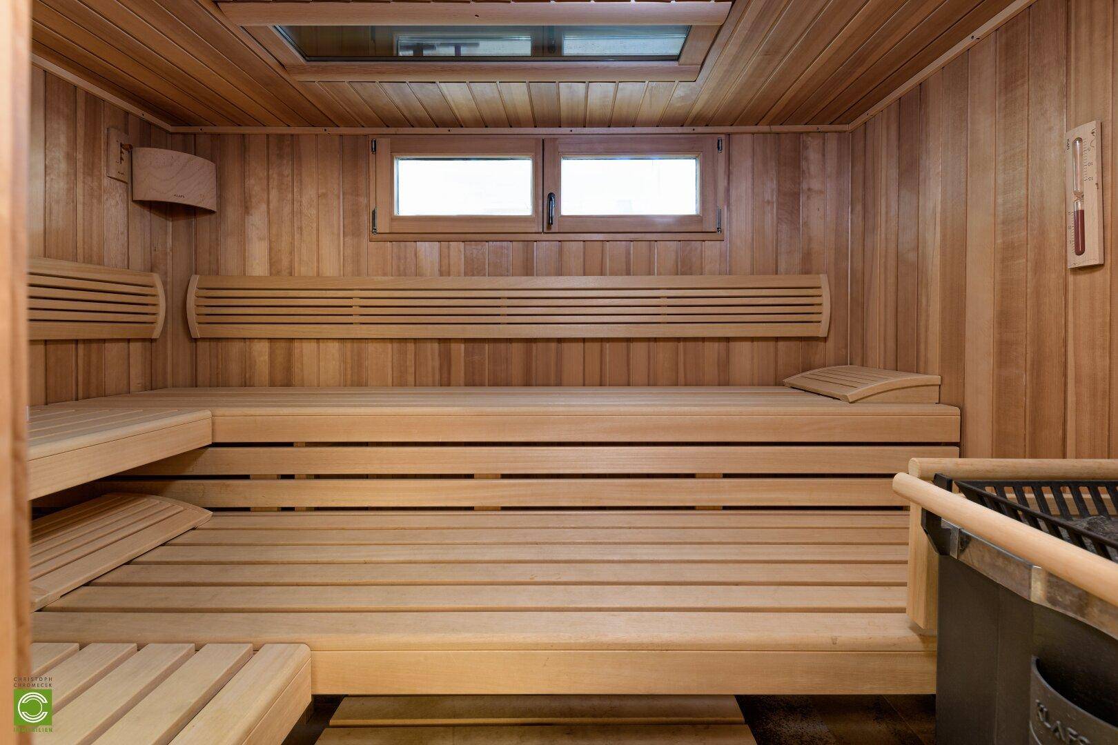 Gemütliche Holzsauna mit mehreren Bänken und einem Fenster für natürliche Belüftung.