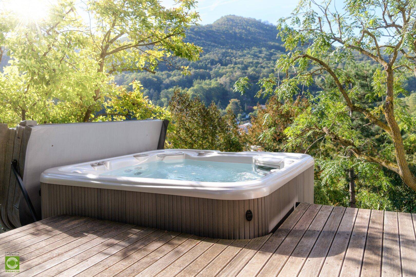 Entspannender Whirlpool auf der Holzterrasse mit malerischem Blick auf die umliegende Berglandschaft.