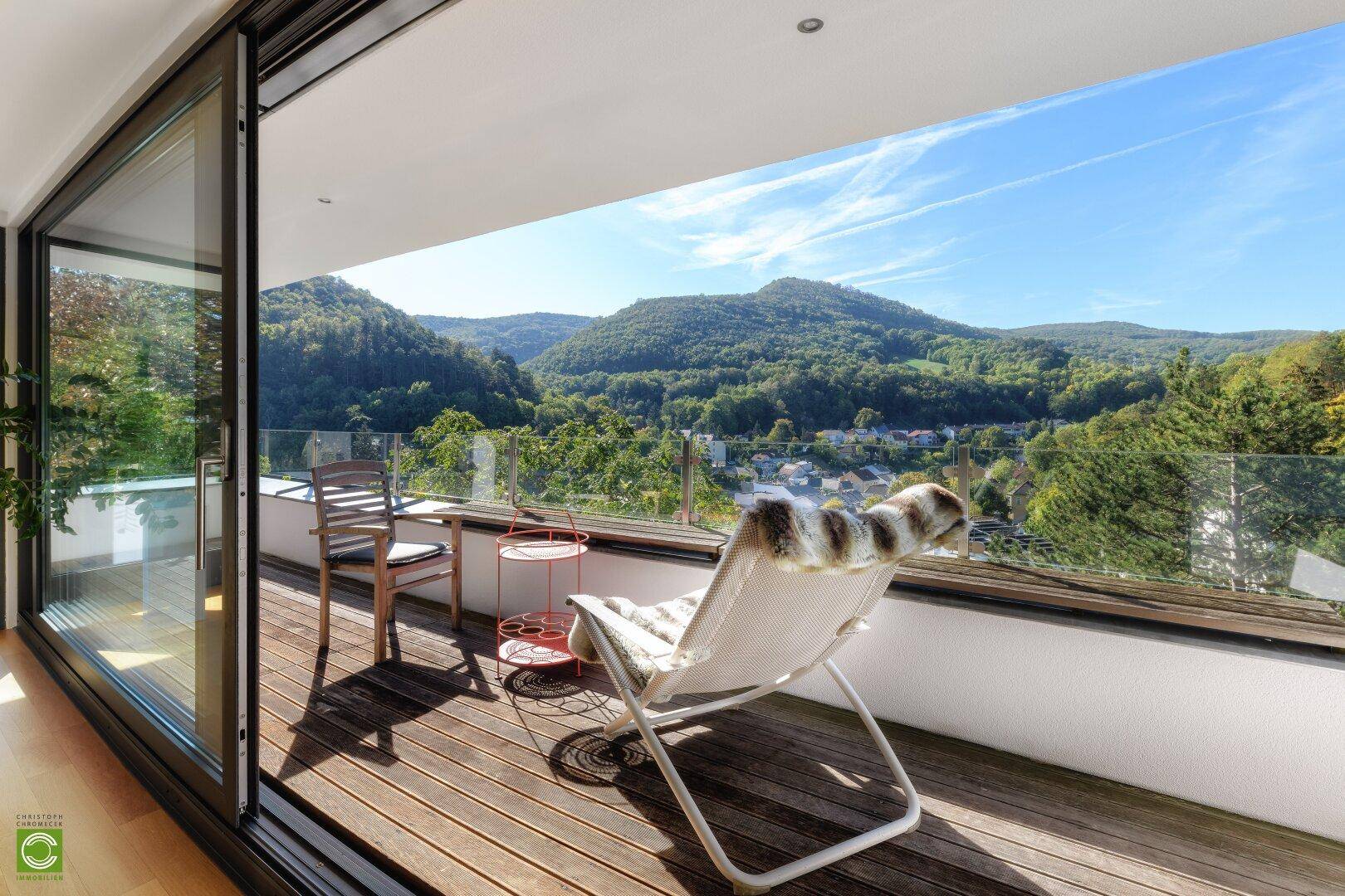 Heller Balkon mit bequemen Liegestühlen und atemberaubendem Panoramablick auf die Berge.