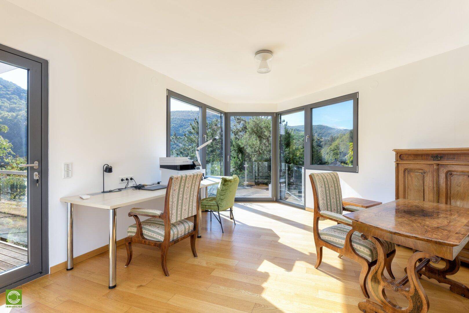 Helles Arbeitszimmer mit großen Fenstern und Panoramablick auf die umliegende Berglandschaft.