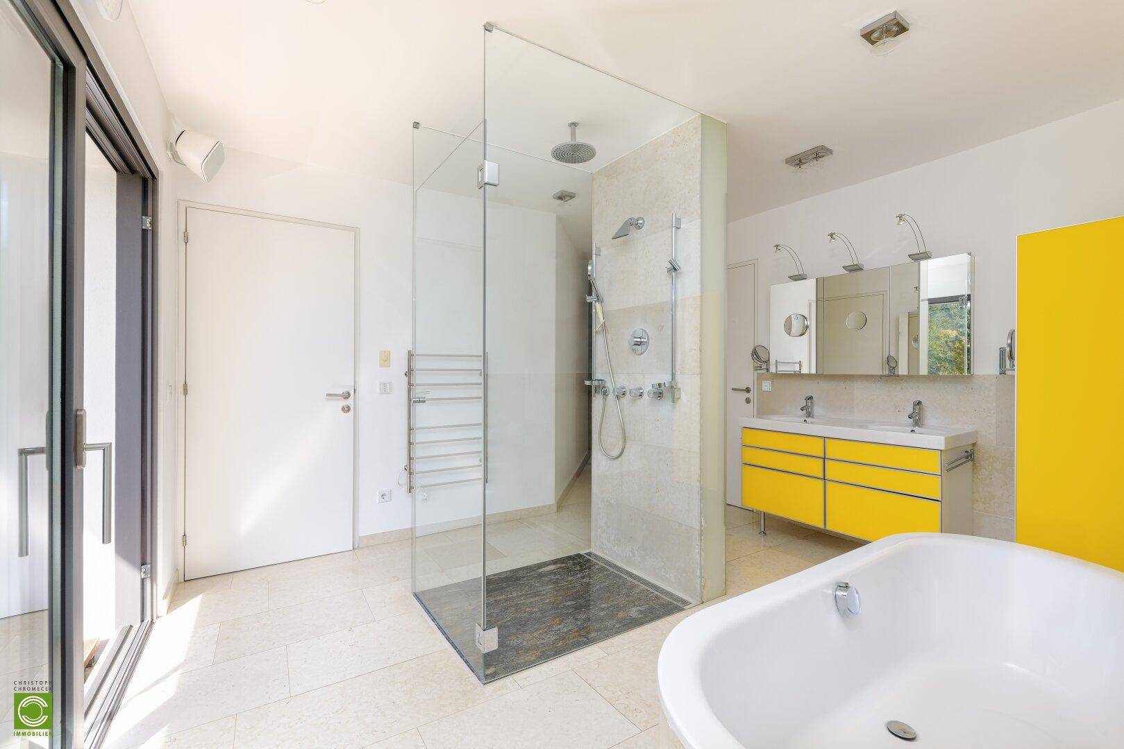 Modernes Badezimmer mit begehbarer Dusche, Badewanne und Doppelwaschbecken in Gelb.