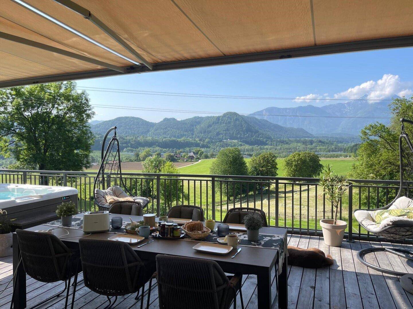Geräumiger Balkon mit Esstisch, Whirlpool und Hängesesseln, bietet einen weiten Bergblick.