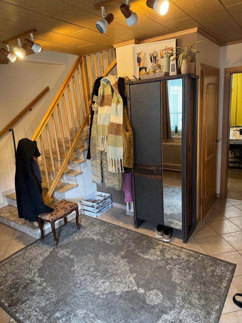 Gemütlicher Eingangsbereich mit Holztreppe, Fliesenboden und Garderobenschrank.