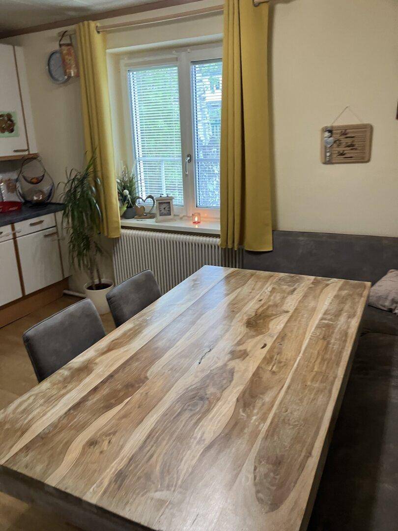 Heller Essbereich mit großem Holztisch und Blick aus dem Fenster.