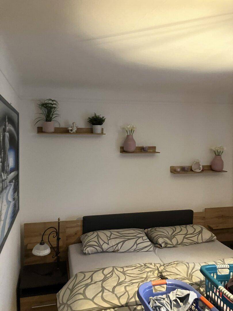 Schlafzimmer mit Doppelbett, Nachttischen und dekorativen Wandregalen.