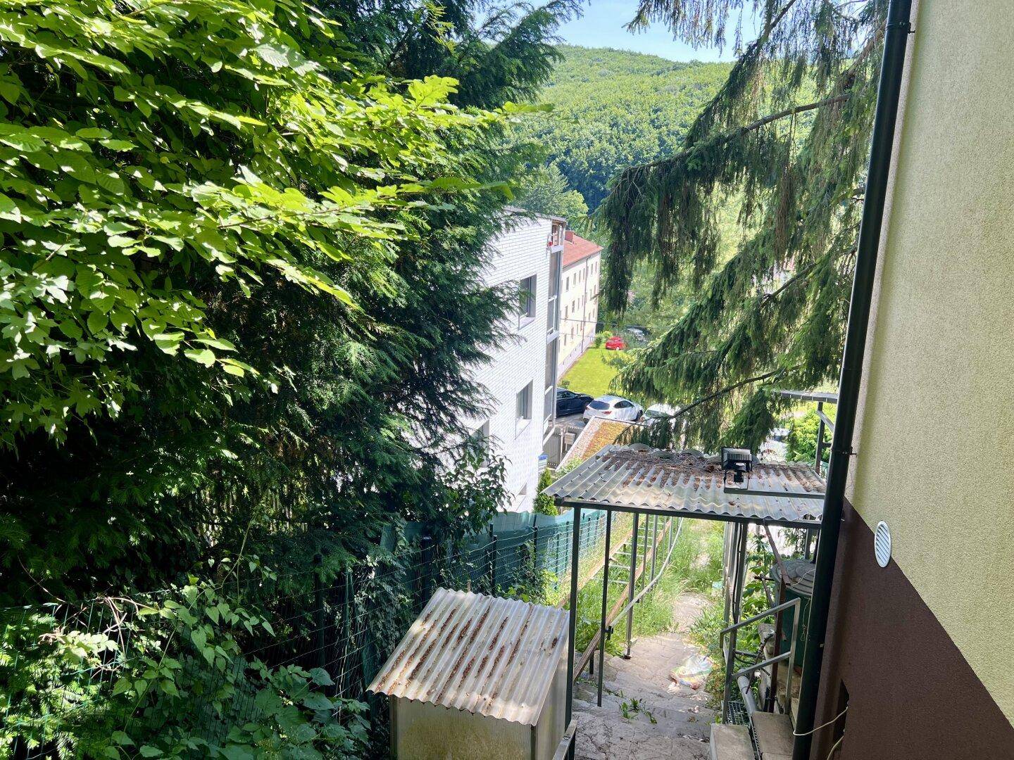 Blick von einem Gebäude einen steilen, bewachsenen Pfad hinunter zu einem weiteren weißen Gebäude.