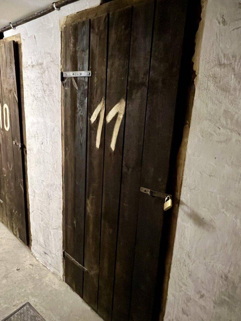 Kellerabteil mit Holztür und der Nummer 11, in einem langen Kellergang.