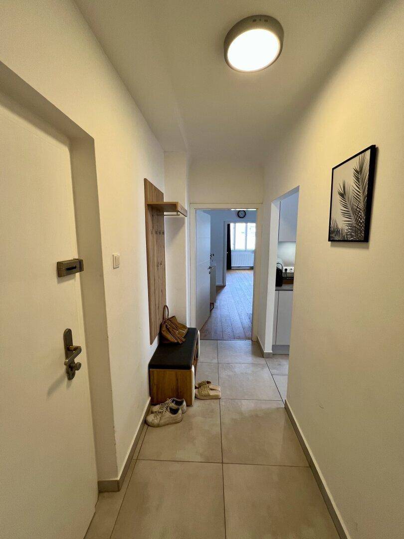 Langer Flur mit Fliesenboden, Garderobe und Blick in die angrenzenden Räume.