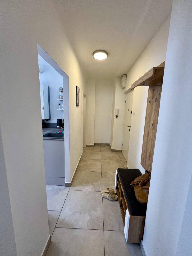 Heller Flur mit Fliesenboden und einer Garderobe, die zum Eingangsbereich führt.