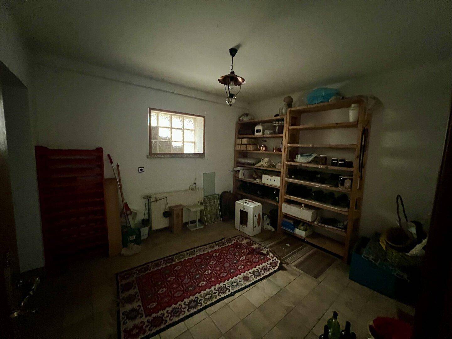 Abstellraum mit Holzregalen, Fliesenboden und einem Fenster, das Tageslicht hereinlässt.