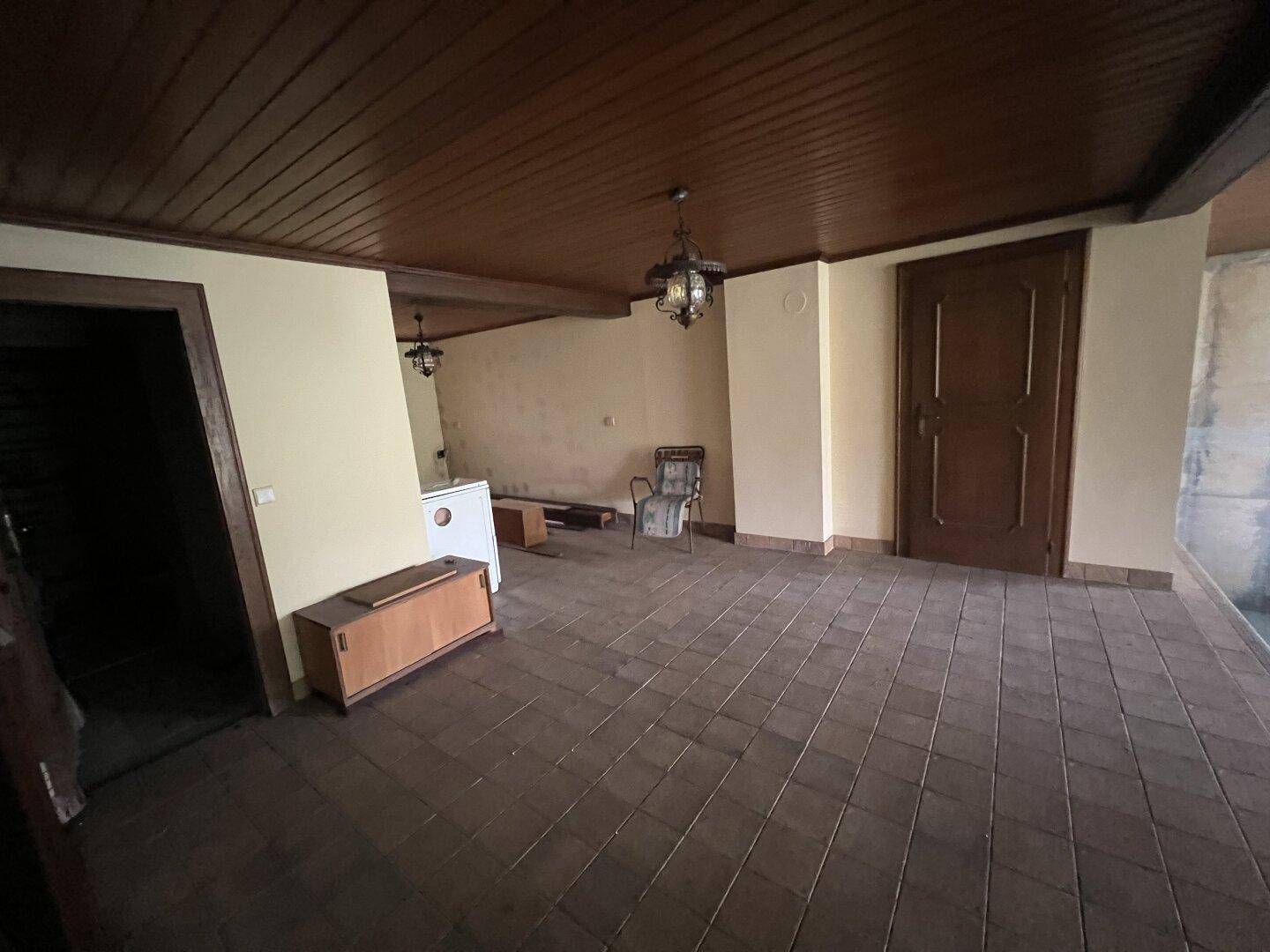 Geräumiger Kellerraum mit Fliesenboden und Holzdecke, angrenzend an den Poolbereich.