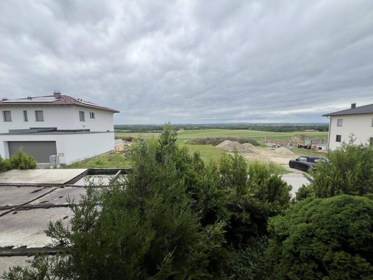 Weitläufiger Blick über die ländliche Umgebung mit Feldern und benachbarten Häusern.