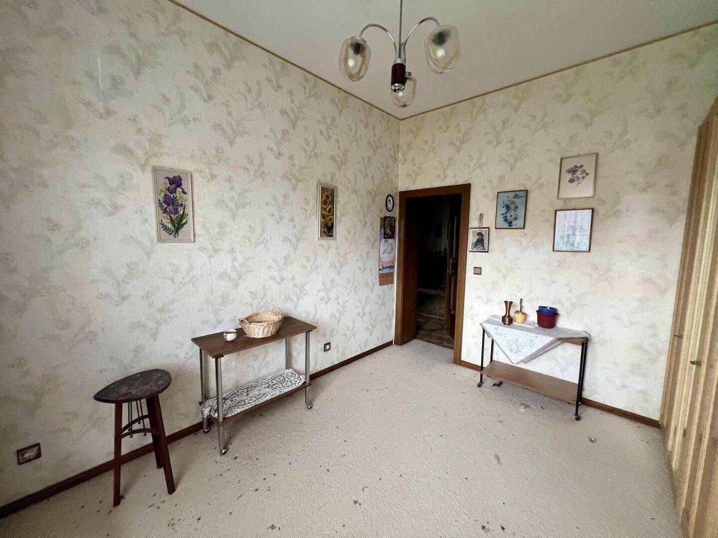 Esszimmer oder zusätzlicher Wohnraum mit gemusterter Tapete und Teppichboden.