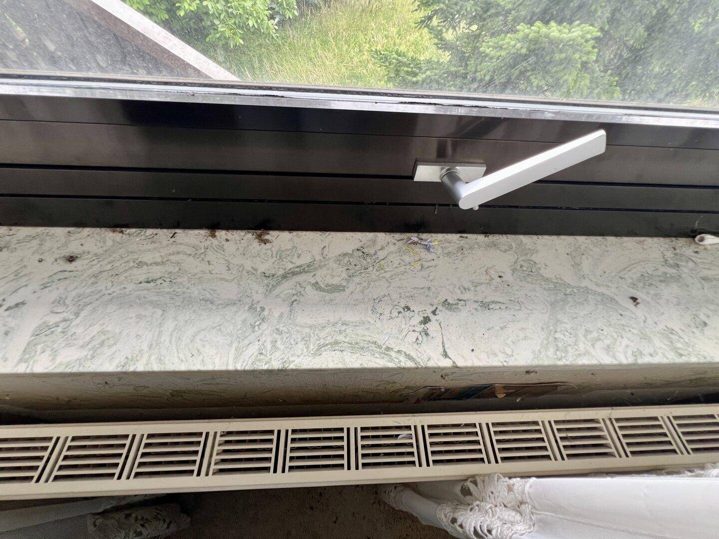 Detailaufnahme eines Fensters mit Fensterbank und Heizkörper darunter, zeigt Gebrauchsspuren.