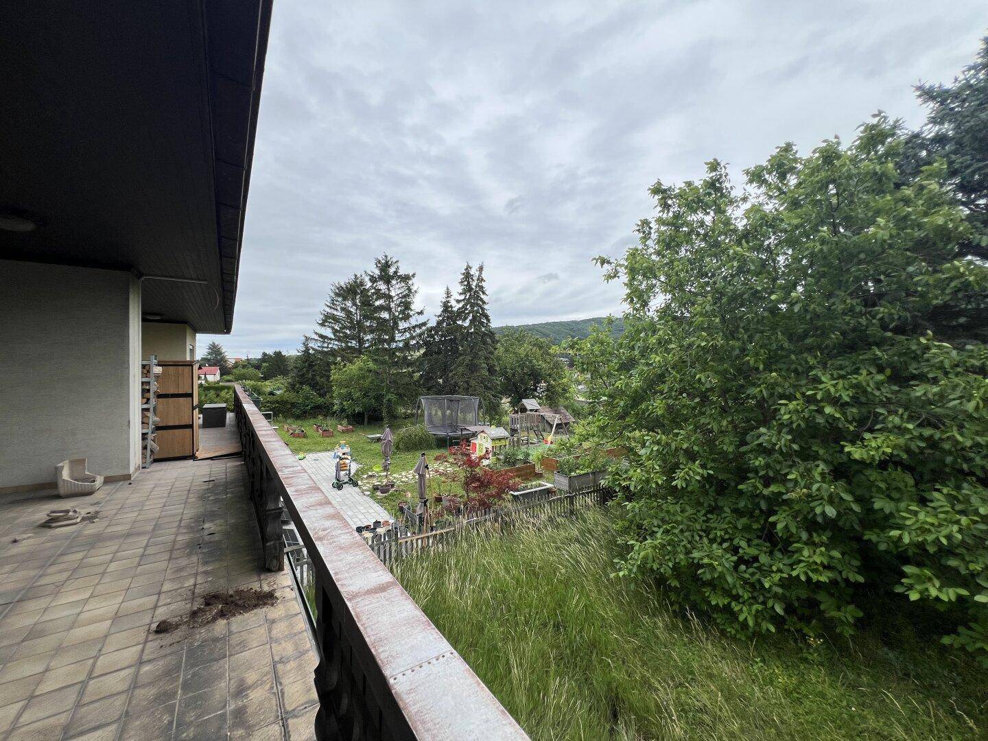 Balkon mit Blick auf den Garten und die umliegende grüne Landschaft.