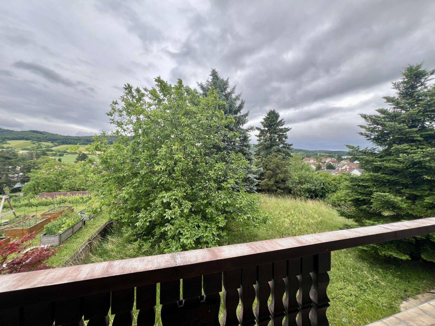 Balkon mit weitem Blick über die grüne Landschaft und angrenzende Gärten.