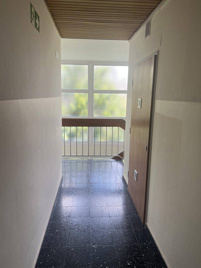 Flur auf einer Etage mit Blick auf das Treppenhaus und eine Wohnungstür.