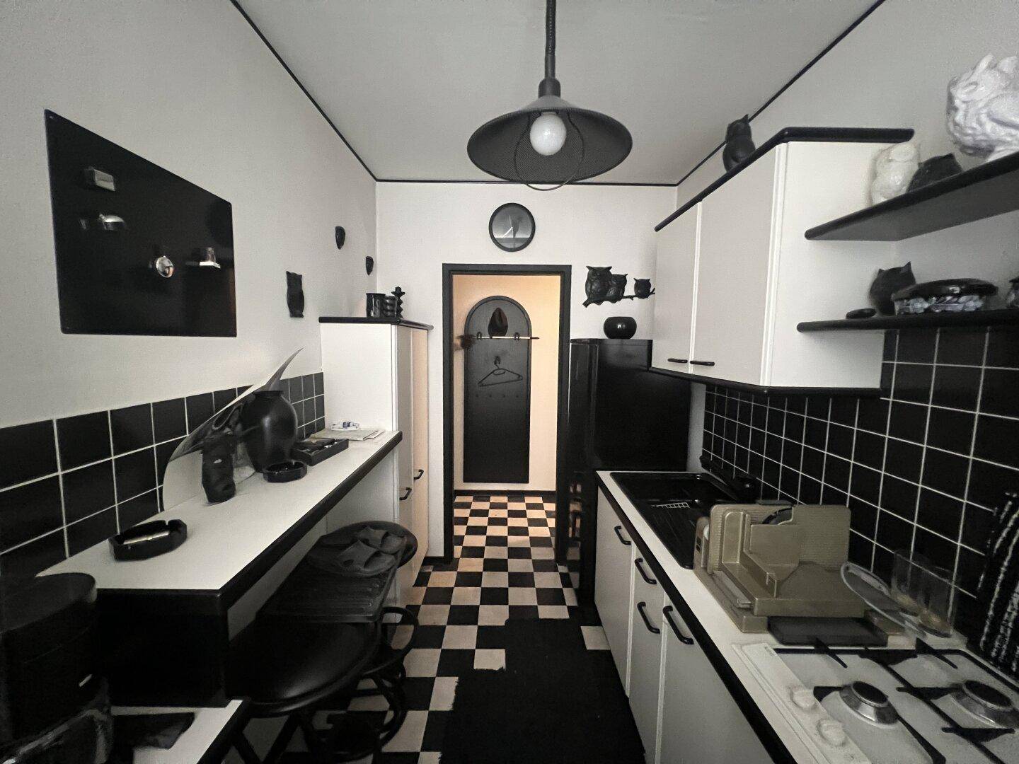 Kleine Küche im Schwarz-Weiß-Design mit kariertem Boden und funktionalen Geräten.