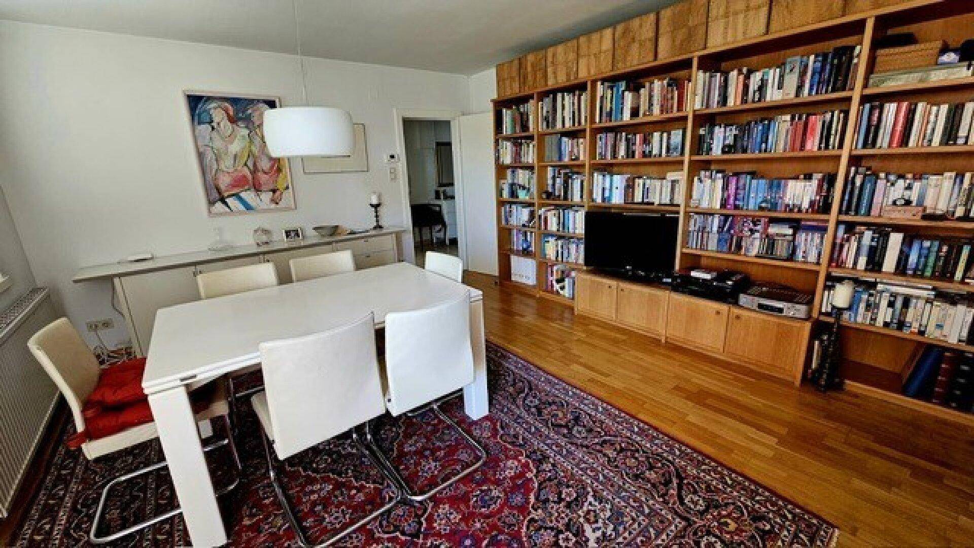 Heller Essbereich mit modernem Esstisch und Stühlen, angrenzend an eine Bücherwand.