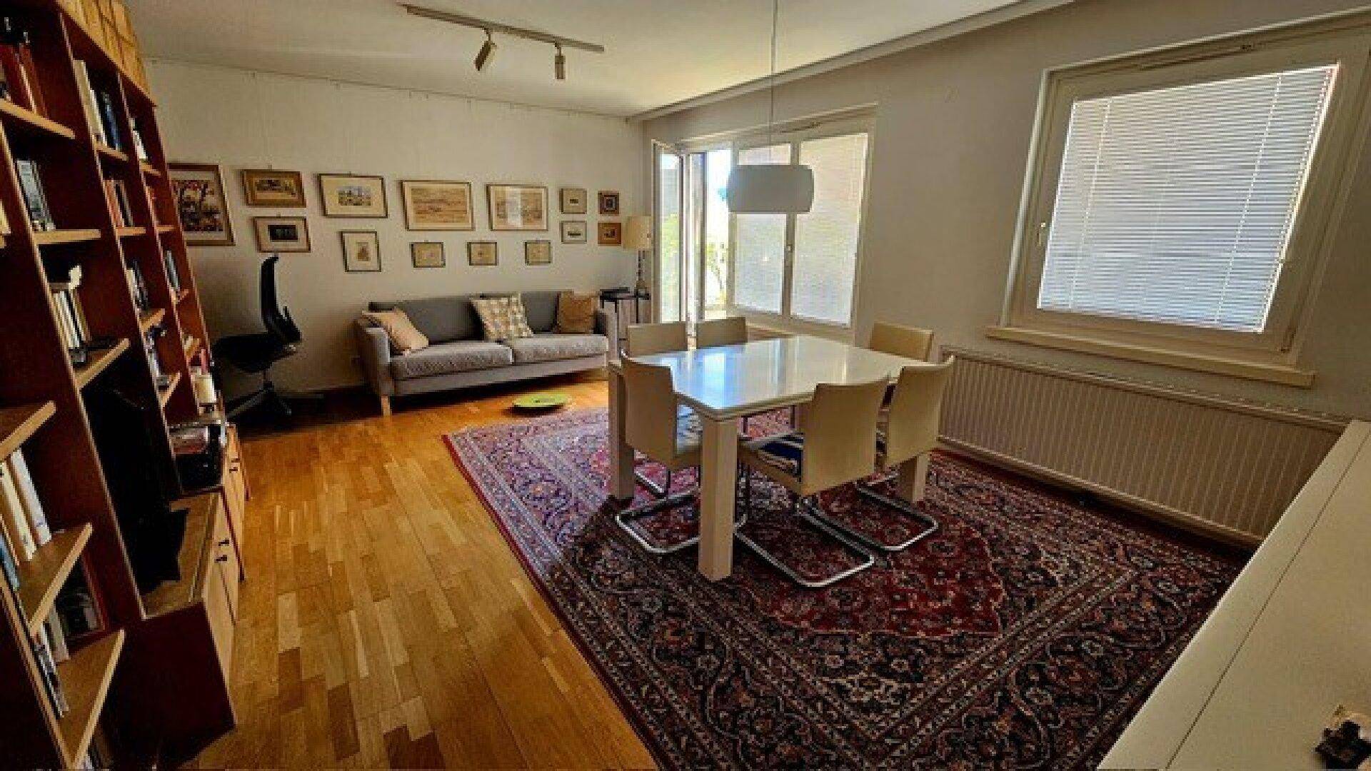 Heller Wohn-Essbereich mit Esstisch, Sofa und großer Bücherwand.