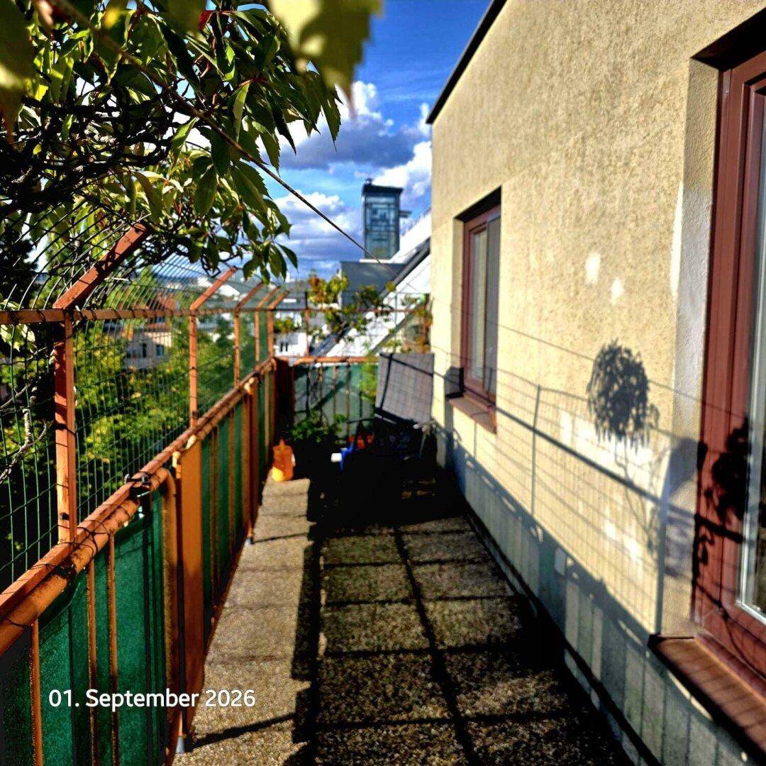 Schmaler Balkon mit Blick auf die Stadt und umliegende Gebäude, umgeben von viel Grün.