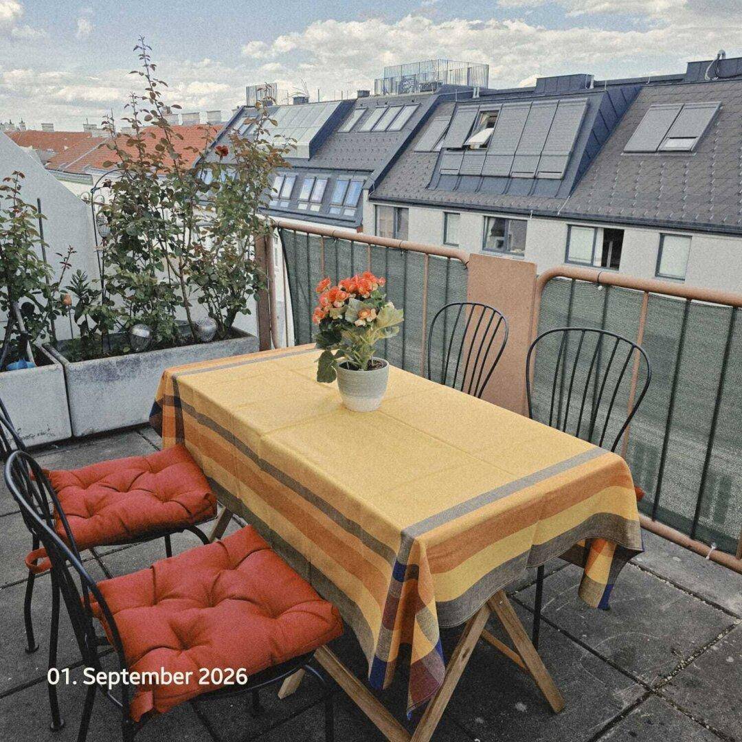 Geräumige Terrasse mit Esstisch, bequemen Stühlen und Blick über die Dächer der Stadt.