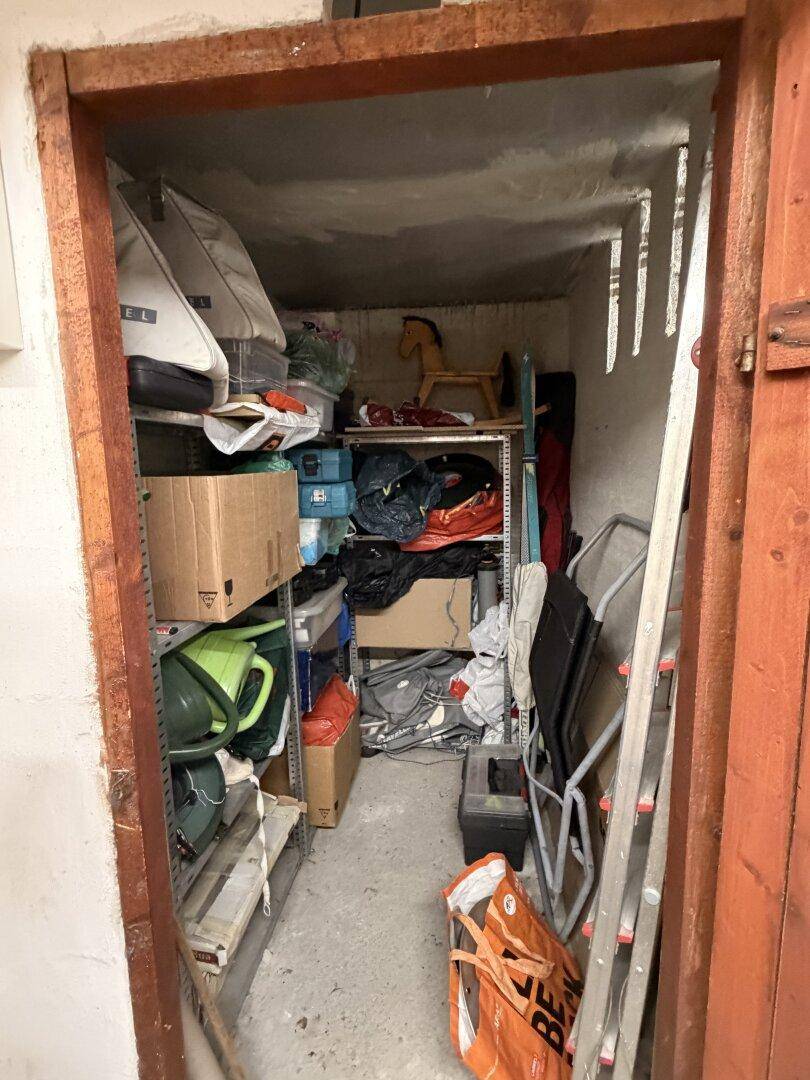 Kleiner, vollgestellter Abstellraum mit Regalen und verschiedenen Haushaltsgegenständen.
