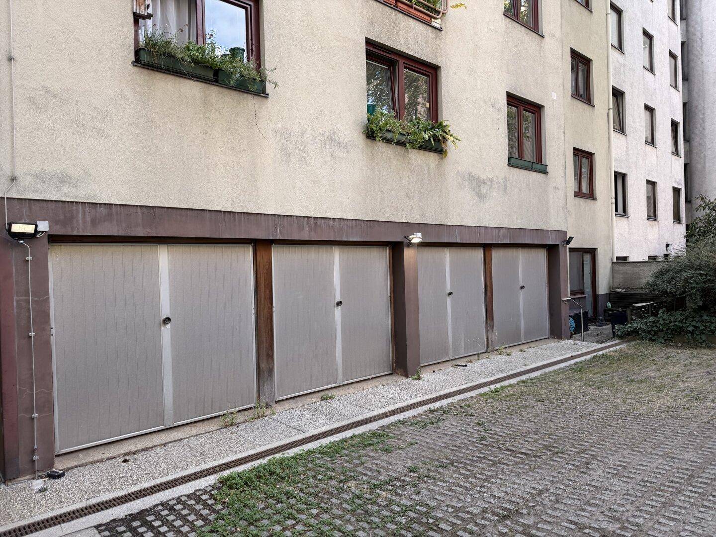 Außenansicht des Gebäudes mit mehreren Garagentoren und einem gepflasterten Vorplatz.