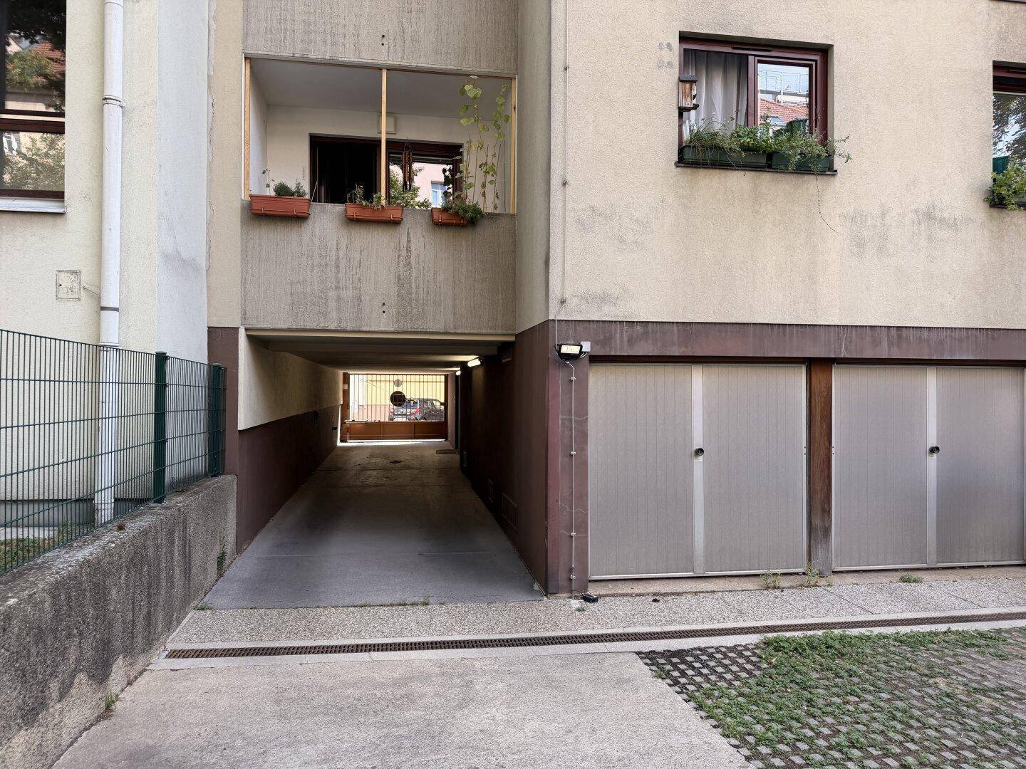 Gebäudefassade mit Zufahrt zu einer Tiefgarage und weiteren Garagentoren im Erdgeschoss.
