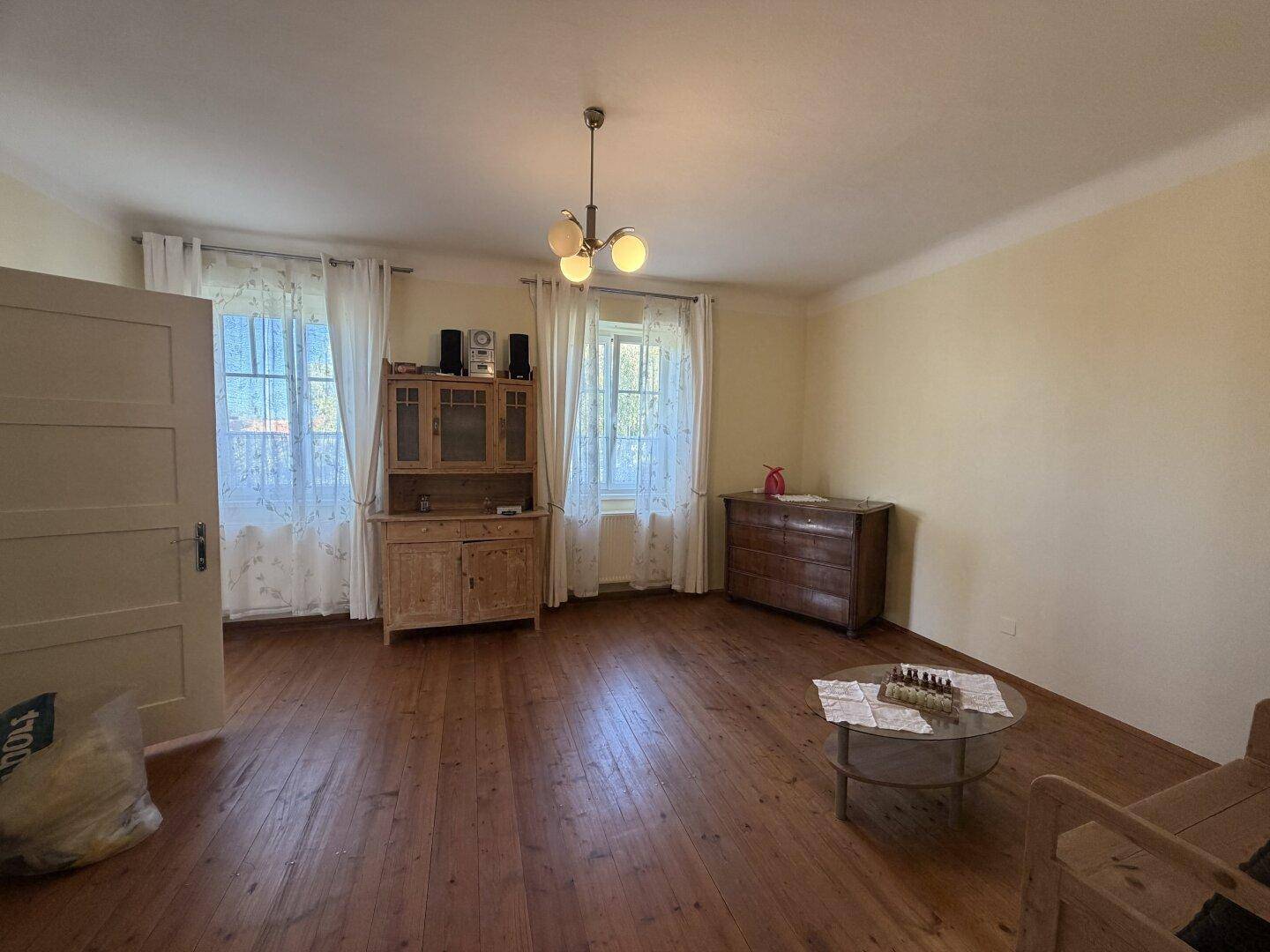 Helles Wohnzimmer mit traditionellem Holzfußboden, gelben Wänden und klassischer Einrichtung.