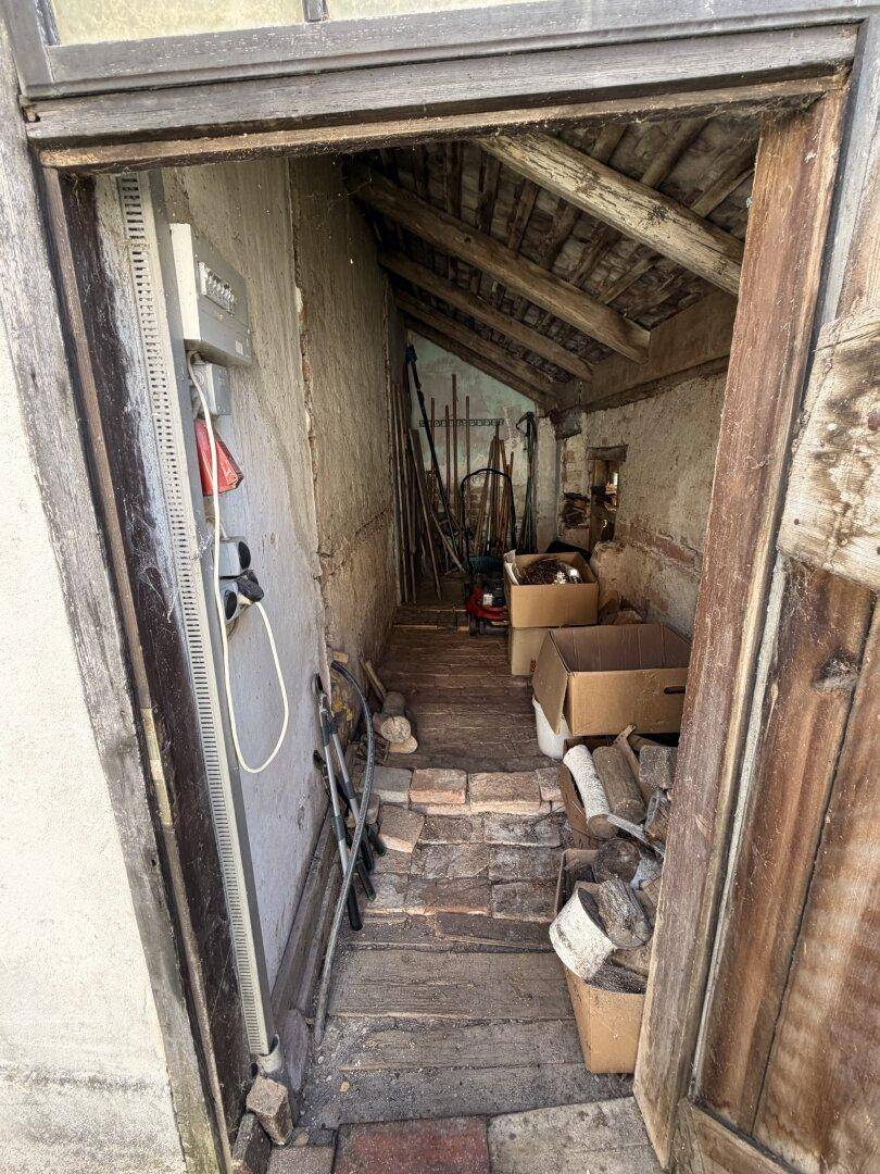 Schmaler Abstellraum mit Werkzeugen, Kisten und sichtbaren Holzbalken, ideal für Lagerung.
