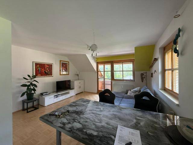 Heller Wohn- und Essbereich mit Holzboden, großem Esstisch und Zugang zum Balkon.