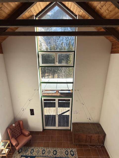 Hohe Fensterfront im Wohnbereich mit Blick auf die umliegende Berglandschaft und Wald.