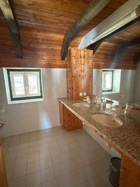 Geräumiges Badezimmer mit Doppelwaschbecken, Granitplatte und Holzelementen unter dem Dach.