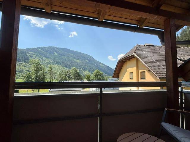 Gemütlicher Balkon mit Holzbalken und weitem Blick auf die umliegenden grünen Berge.