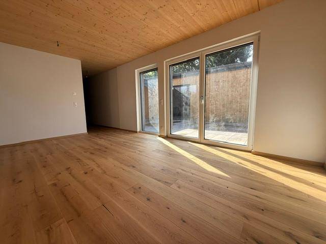 Helles Wohnzimmer mit Eichenparkettboden, Holzdecke und großen Fenstern zum Garten.