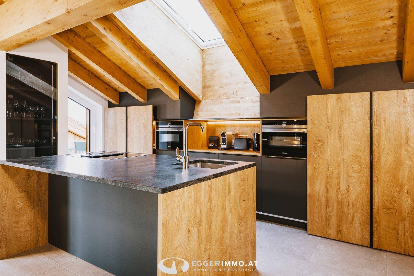 Moderne Küche mit Holzverkleidung, Kücheninsel, Einbaugeräten und einem Oberlicht für viel Licht.