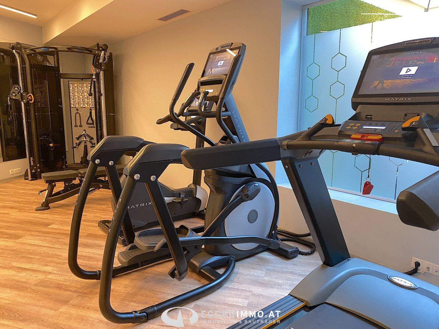Moderner Fitnessraum mit verschiedenen Trainingsgeräten und hellem Ambiente.