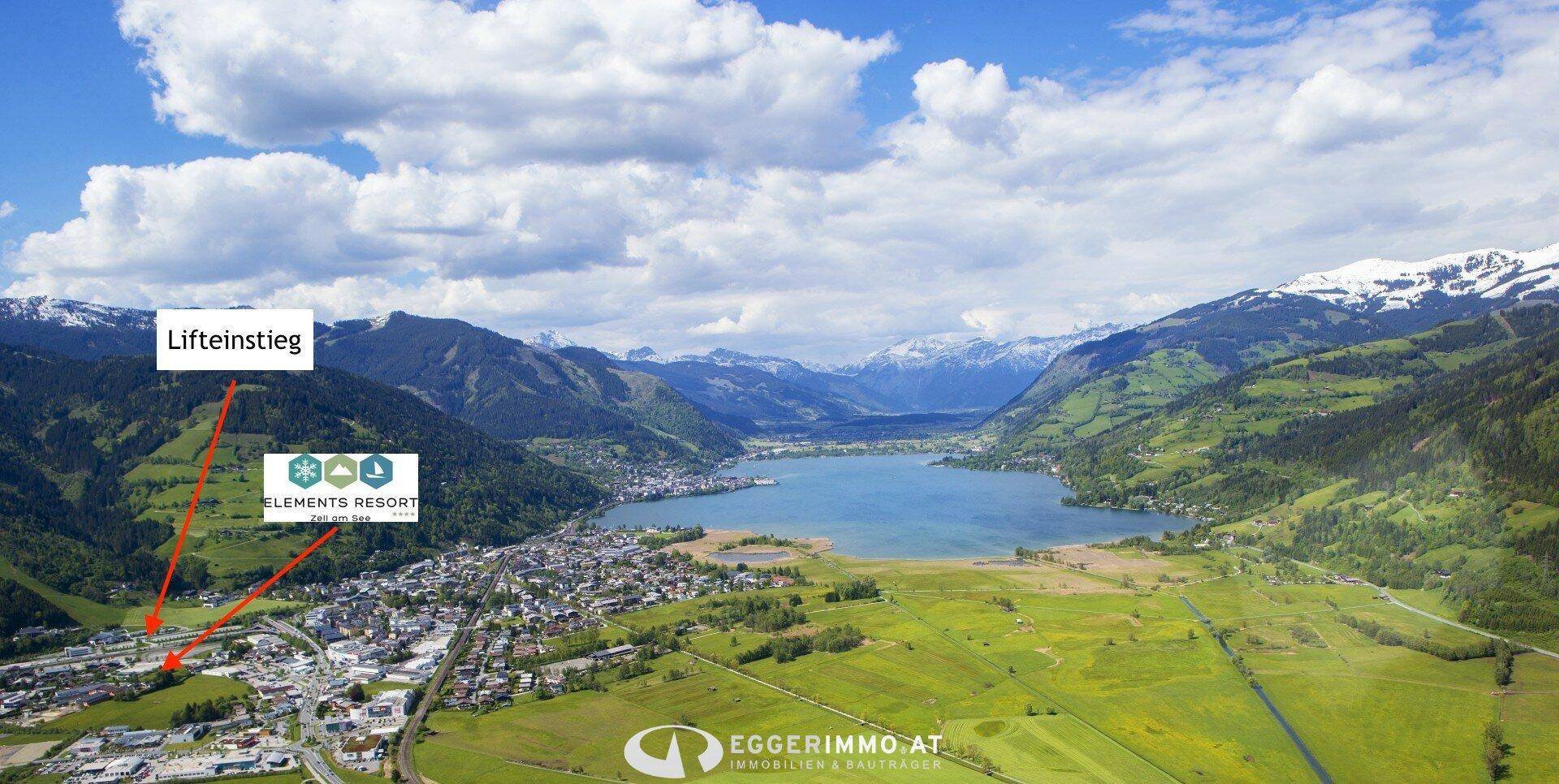 Luftaufnahme der Stadt Zell am See mit See, Bergen und markiertem Resort sowie Liftzugang.
