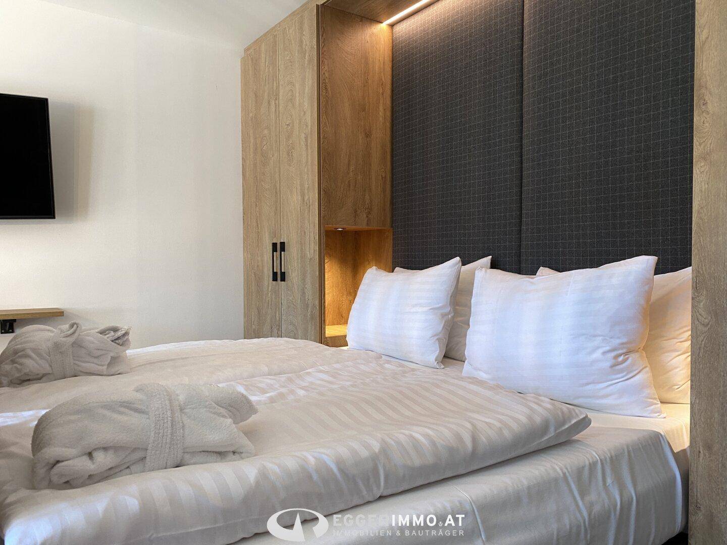 Gemütliches Schlafzimmer mit Doppelbett, Holzelementen und indirekter Beleuchtung für eine entspannte Atmosphäre.