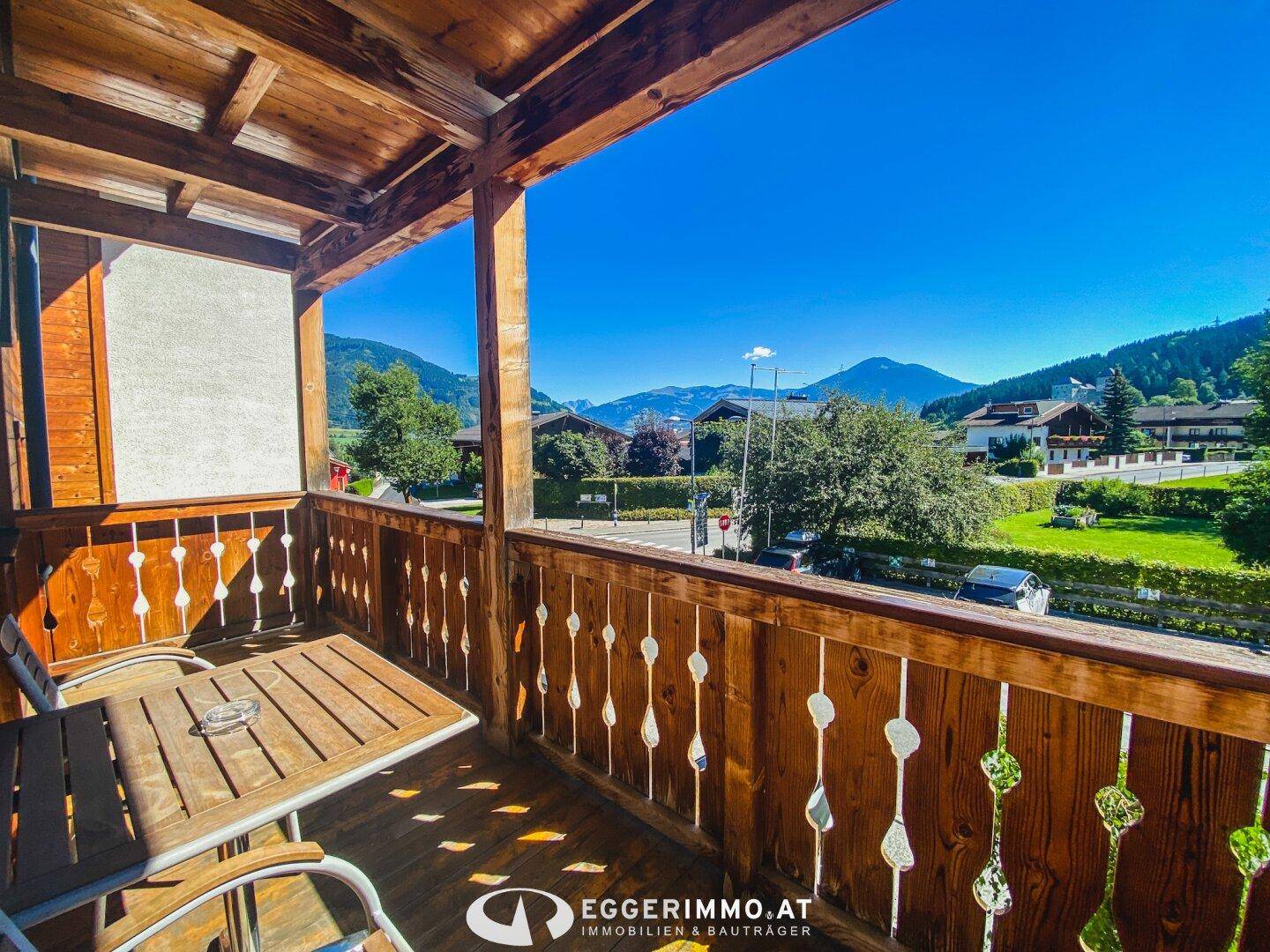 Gemütlicher Balkon mit Holzelementen und Bergblick, ausgestattet mit einem kleinen Tisch und Stühlen.