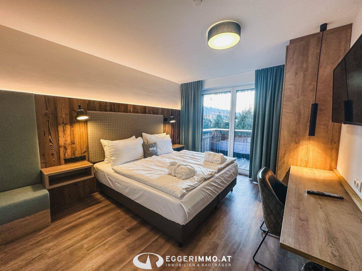 Komfortables Schlafzimmer mit Doppelbett, Holzelementen und direktem Zugang zu einem Außenbereich.