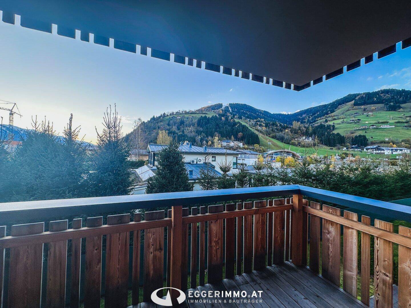 Geräumiger Holzbalkon mit weitem Blick auf die umliegende Berglandschaft und grüne Natur.