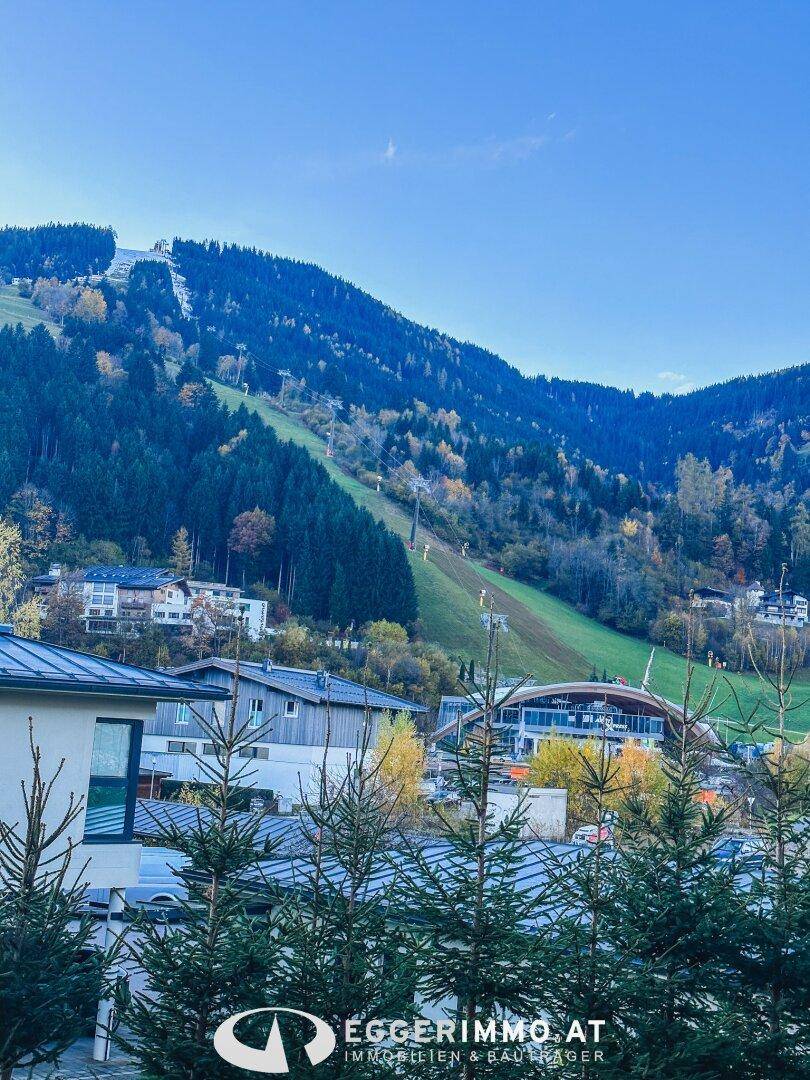 Panoramablick auf die majestätische Berglandschaft mit Skipisten und bewaldeten Hängen.