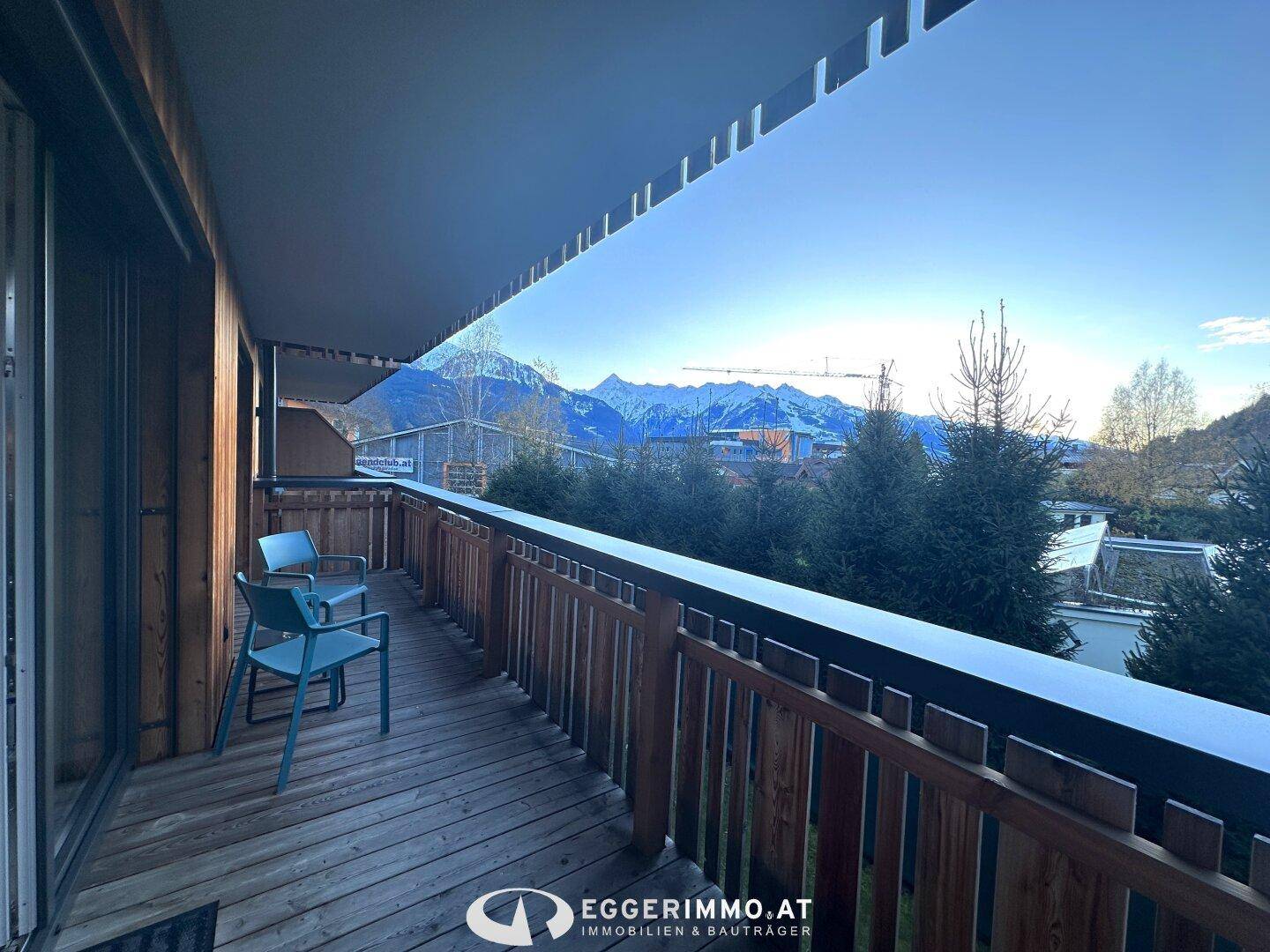 Langer Holzbalkon mit Sitzgelegenheiten und beeindruckendem Blick auf die Berge und das Tal.