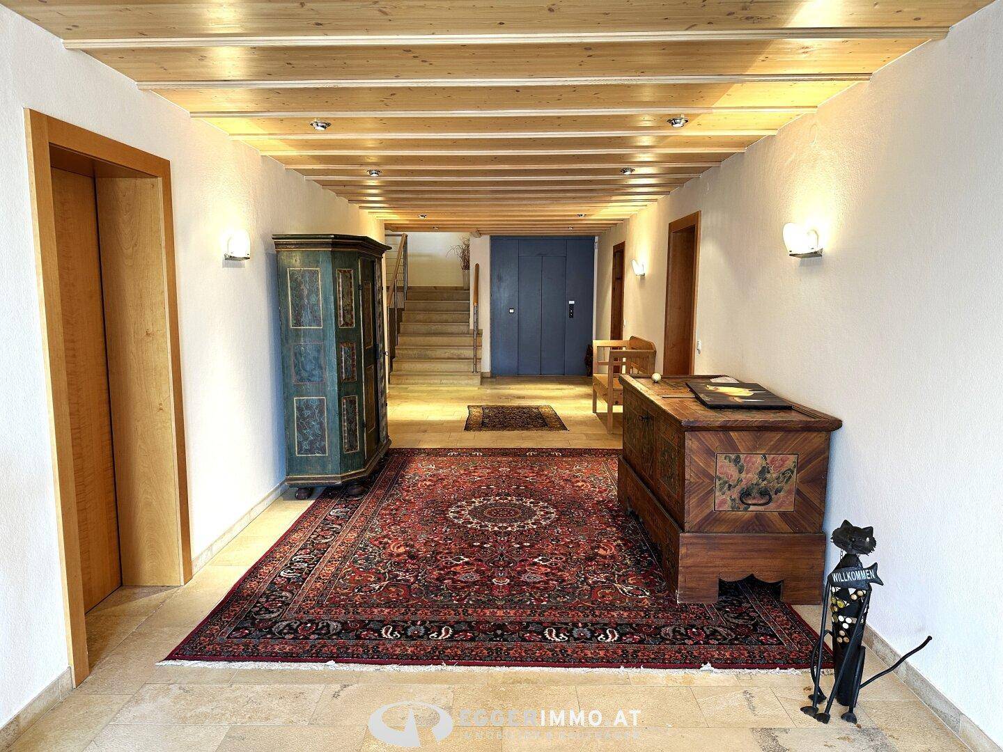 Geräumiger Flur mit traditionellen Holzmöbeln, einem großen Teppich und einer Holzdecke.