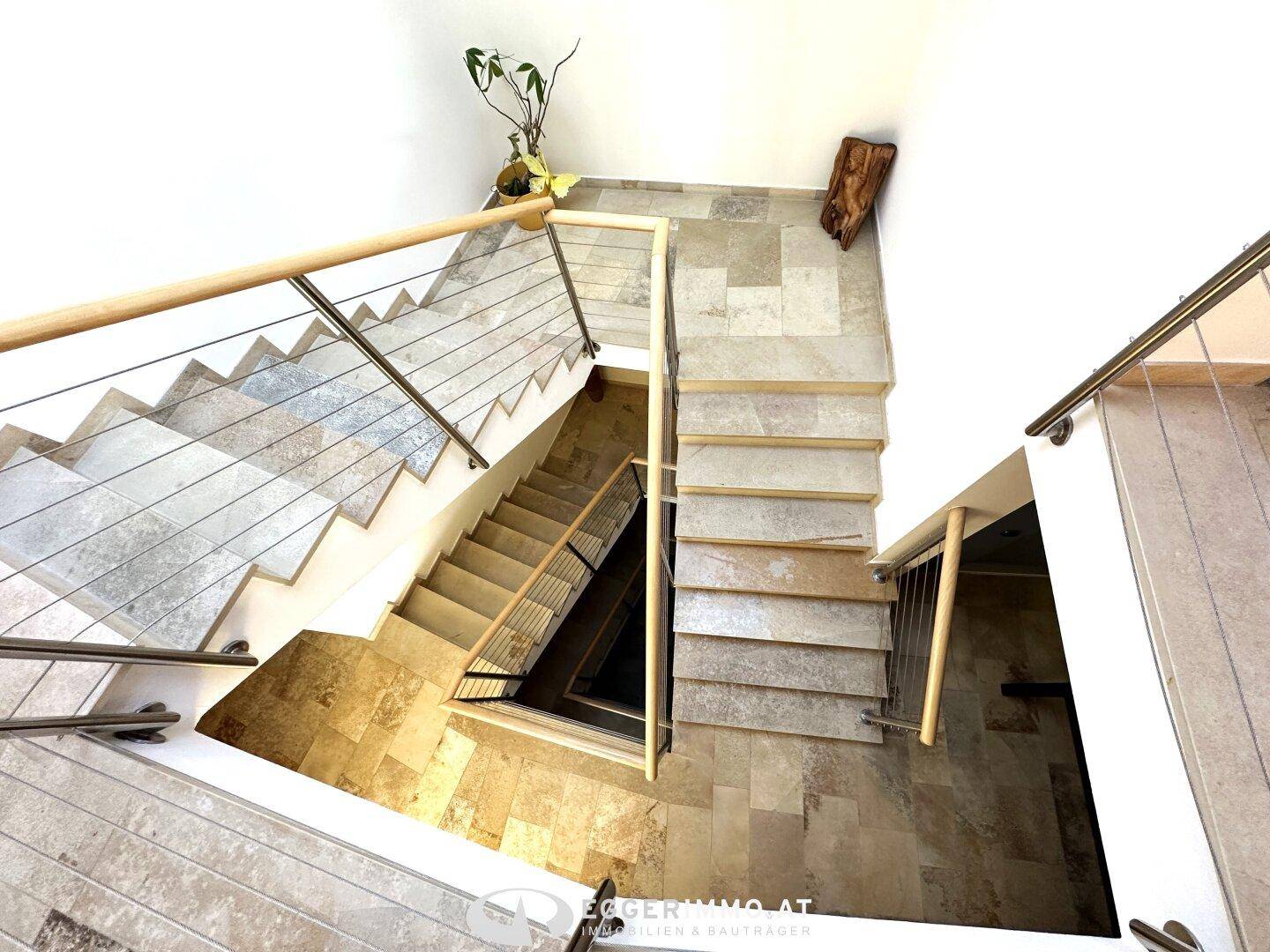 Elegante Treppe mit Steinplatten und modernen Metallgeländern, die verschiedene Ebenen verbindet.