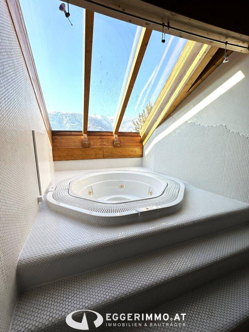 Luxuriöser Whirlpool unter einem Oberlicht mit Bergblick, umgeben von weißen Mosaikfliesen.