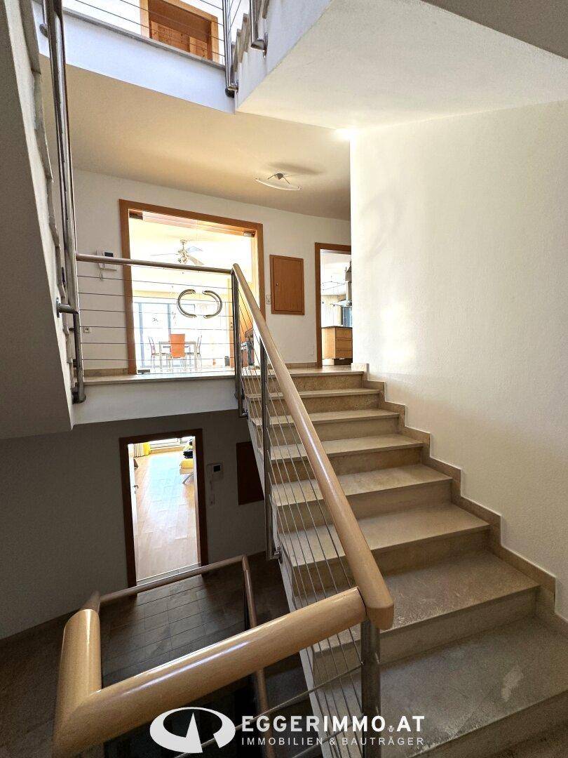 Helle Treppe mit Steinplatten und modernen Geländern, die zu den oberen Etagen führt.